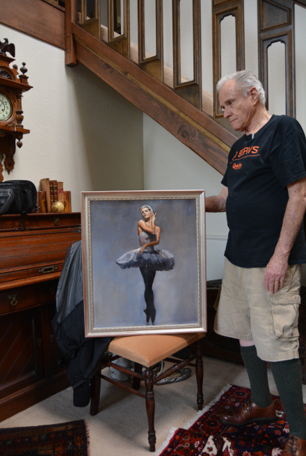 Robert W Moore Fine Art artist standing in the foyer of his beautiful home touching the frame of his signature piece, The Ballerina